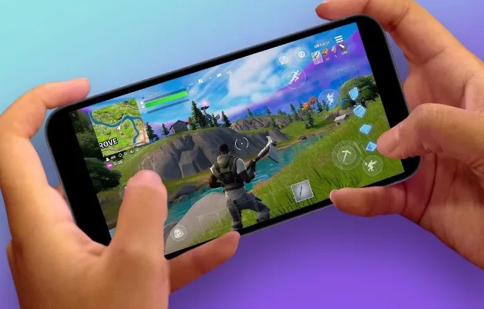 Unas manos que tienen un telefono jugando a Fortnite.